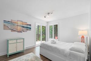 a white bedroom with a bed and a window at Peaceful Condo with Stunning Mountain and Lake Views in Mont-Tremblant