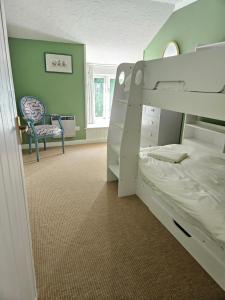a bedroom with a bunk bed and a chair at Brook Barn in Malborough