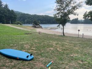 een blauwe surfplank die op het gras naast een strand ligt bij Chalet lac de la Raviege vue lac in La Salvetat +4 foto's