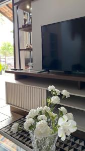 a vase of white flowers sitting on a table in front of a tv at amplo sobrado perto da praia in Florianópolis