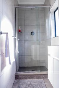 eine Dusche mit Glastür im Badezimmer in der Unterkunft 13 Elizabeth Place - Beautiful 2 bedroom unit next to Kyalami Racetrack with free WiFi - swimming pool gym and restaurant - Perfect for a small family in Midrand Waterfall in Midrand