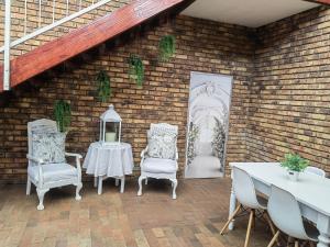 a patio with two tables and two chairs and a brick wall at Zhantique Guest House 2- Unit 12 in Boksburg