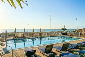 a swimming pool with chairs and the ocean in the background at Town of Rehoboth Beach 4 Maryland Ave in Rehoboth Beach