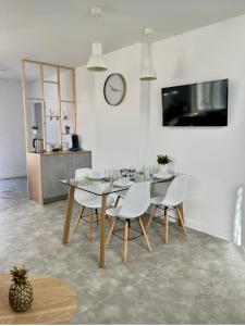a dining room with a table and chairs and a clock at Appartement cosy et calme avec parking et terrasse privés in Cravanche