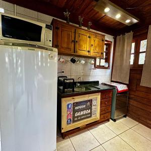 a kitchen with a white refrigerator and a microwave at Refúgio Vista Mar Praia da Gamboa - SC in Garopaba