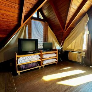 a room with two shelves with a tv in a tent at Refúgio Vista Mar Praia da Gamboa - SC in Garopaba