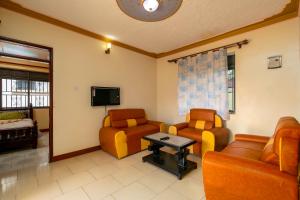 a living room with two chairs and a tv at Rendy partment- KAWUKU in Kisubi