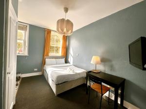a bedroom with a bed and a desk and a television at London Collection - Bayswater in London