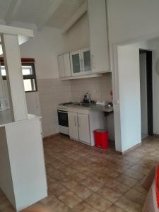 una cocina con armarios blancos y un cubo de basura rojo en Casita de los Andes, en San Carlos de Bariloche