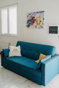 a blue couch in a living room with a painting at Casa degli Ulivi - Apartment A in Porto San Giorgio