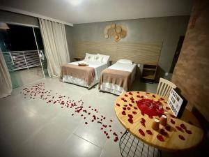 a bedroom with two beds and a table with red hearts on the floor at Pousada Villa Minduba in Japaratinga