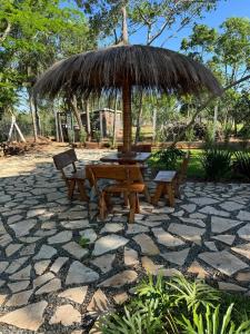 un tavolo da picnic e sedie sotto un ombrellone di paglia di Residencia Piri a Piribebuy Altre 37 foto
