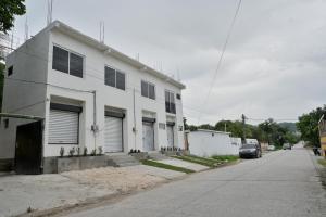a white house on a street with a driveway at Apartamentos Petenchel, por Aeropuerto Flores Peten no 3 in Santa Elena