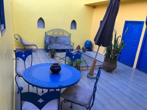 un patio con tavolo, sedie e letto di Riad Le Lieu a Tiznit