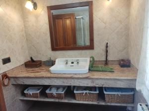 a bathroom with a sink and a mirror and baskets at Casa Rural A Eira Vella in Padrón +16 photos