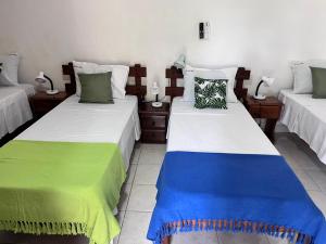 a room with two beds with green and blue at Recanto das Flores Suite Quádruplo in Barra de Santo Antônio