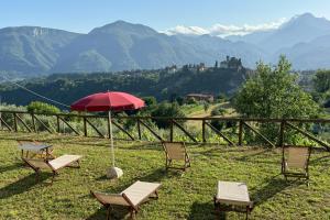 two chairs and a table and an umbrella in the grass at Family Friendly Rosa House Amazing View - Happy Rentals in Barga