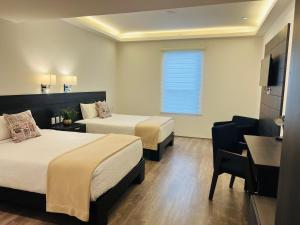 Una habitación de hotel con dos camas y un escritorio. en QA Hotel, en San Luis Potosí
