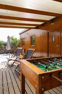a wooden deck with a pool table and chairs at Porto Maia Garden in Maia