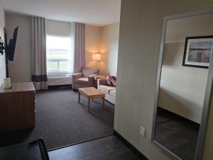 a hotel room with a chair and a couch and a mirror at The Kanata Bonnyville in Bonnyville