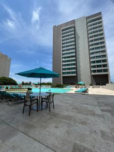 a table and chairs with an umbrella in front of a building at Bello Horizonte-sector Hilton -irotama in Playa Bello Horizonte