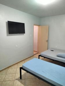 a room with two beds and a flat screen tv at Apto 6 ótimo local próximo shopping in Campo Grande