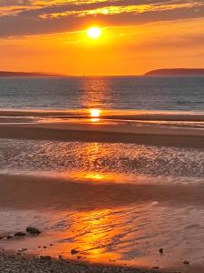 - un coucher de soleil sur une plage bien exposée dans l'établissement Fantastic sea views at Century's old Alma's Cottage - Sleeps up to 8 guests, à Penmaen-mawr