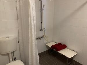 La salle de bains est pourvue de toilettes, d'une douche et d'une serviette rouge. dans l'établissement Weipa Motel Resort, à Weipa 7 autres photos