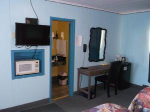 Habitación con escritorio y TV en la pared. en Haileybury Beach Motel, en Haileybury