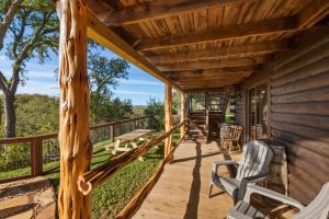 a porch of a log cabin with chairs and tables at Guadalupe Bluff Log Cabin in Kerrville +37 photos