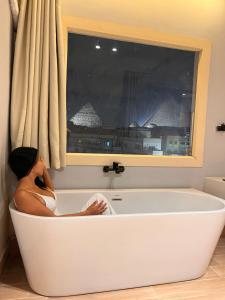 una donna seduta in bagno in una vasca da bagno di NUT Pyramids Hotel a Il Cairo
