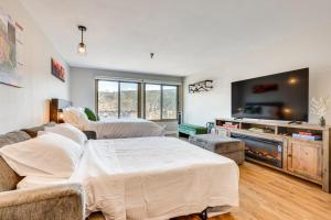 a living room with two beds and a flat screen tv at Walk to Dtwn Winter Park Studio with Hot Tub Access in Winter Park
