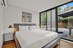 une chambre avec un grand lit et une grande fenêtre dans l'établissement Canopy - Boutique Elwood Luxury with parking, à Melbourne