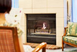 een vrouw die voor een open haard zit bij Tokyu Vacations Karuizawa in Karuizawa