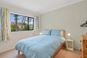 una camera da letto con un letto e una grande finestra di Birch Cottage - Greytown Holiday Home a Greytown