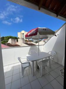 a table and chairs and an umbrella on a balcony at Triplex White em Caiobá-Matinhos-Pr a 200 mt do mar in Matinhos