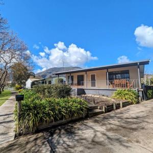 a house with a porch and a yard with plants at Cupie's Cabin in Talbingo