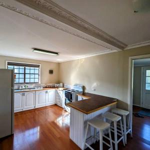 a kitchen with white cabinets and a table and stools at Cupie's Cabin in Talbingo