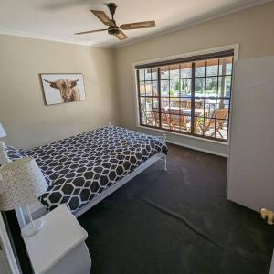 a bedroom with a bed with a cow picture on the wall at Cupie's Cabin in Talbingo