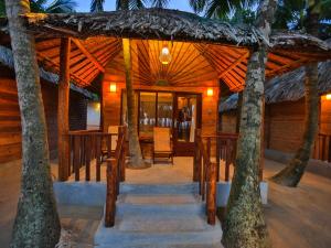 Casa de madera con mesa, sillas y palmeras en Thejan Beach Cabanas, en Bentota