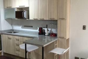 eine Küche mit weißen Schränken und einer Theke mit Stühlen in der Unterkunft Concepción pleno centro in Concepción