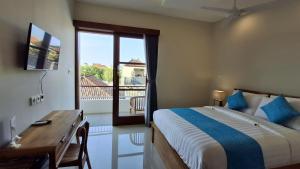 沙努尔Kutus Bali Guesthouse的一间卧室，配有一张床、一张书桌和一扇窗户