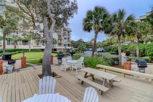 a deck with two chairs and a picnic table and a tree at 3422 Villamare Updated Luxury 2 BR Ocean & Pool Views King 2 Queens Sleeps 6 in Hilton Head Island