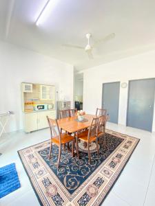 a dining room with a table and chairs on a rug at Dramayu Homestay in Cukai +6 photos