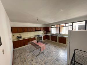 an empty kitchen with a table and a refrigerator at Casa Nana , amplia y tranquila in Yelateni