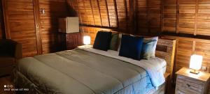 a bedroom with a bed with blue pillows at Sugita Wooden House 2 in Payangan