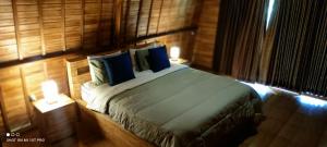 a bedroom with a large bed with blue pillows at Sugita Wooden House 2 in Payangan