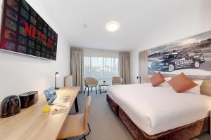 巴瑟斯特Littomore Hotel on Stewart, Bathurst的一间配有床和带笔记本电脑的书桌的酒店房间