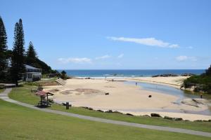 Una playa con gente en la arena y el océano. en Pacific Court 1 - Bring your own linen., en South West Rocks