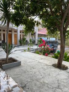 une cour avec des arbres et des fleurs devant un bâtiment dans l'établissement ABC Guest House Labuan Bajo, à Labuan Bajo
